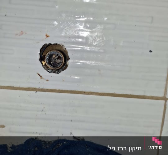 חור בקיר עם ברז מתכת וחולצה כחולה